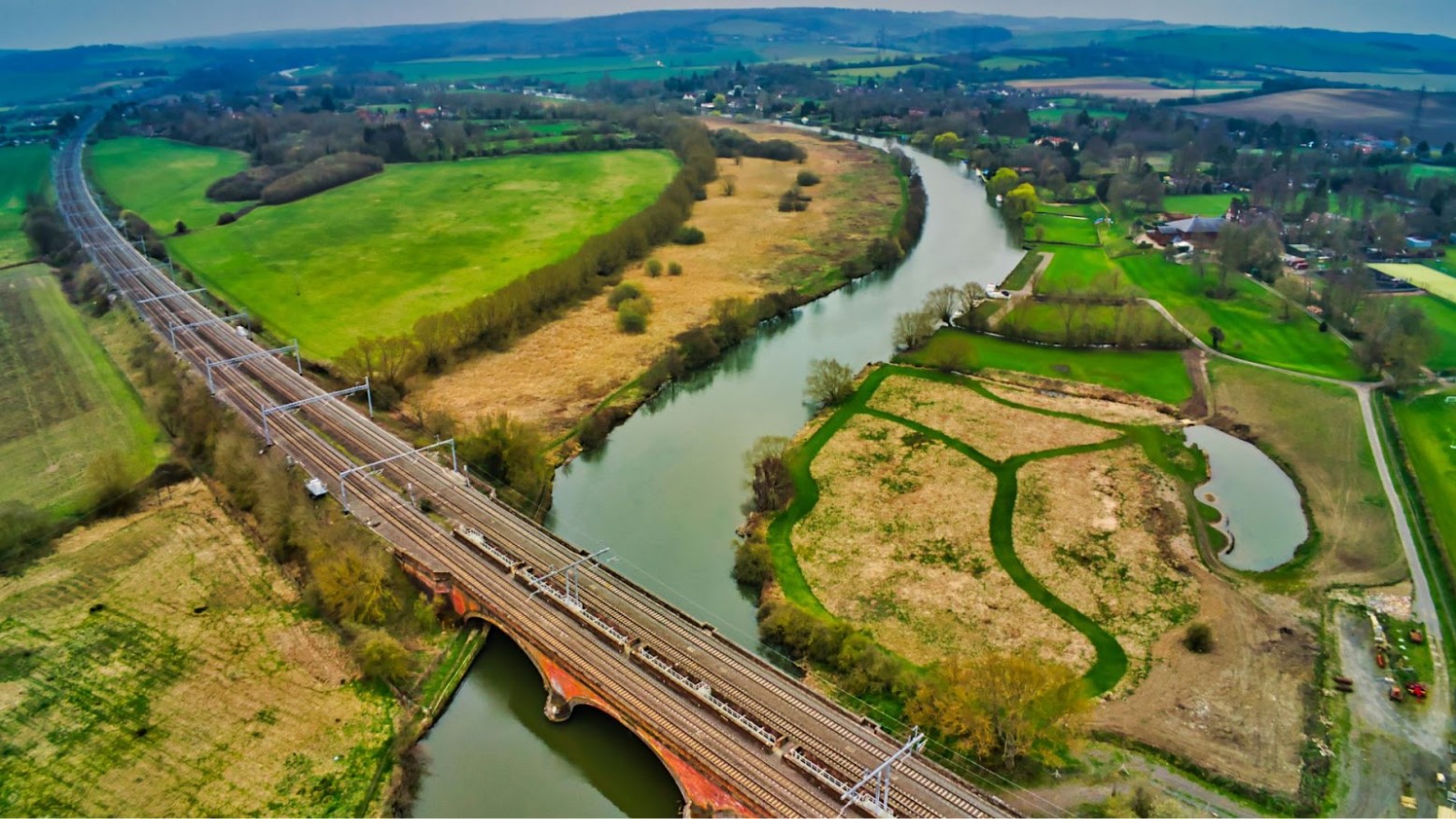 An aerial view of a road and bridge over a river in Oxfordshire, England during the daytime.