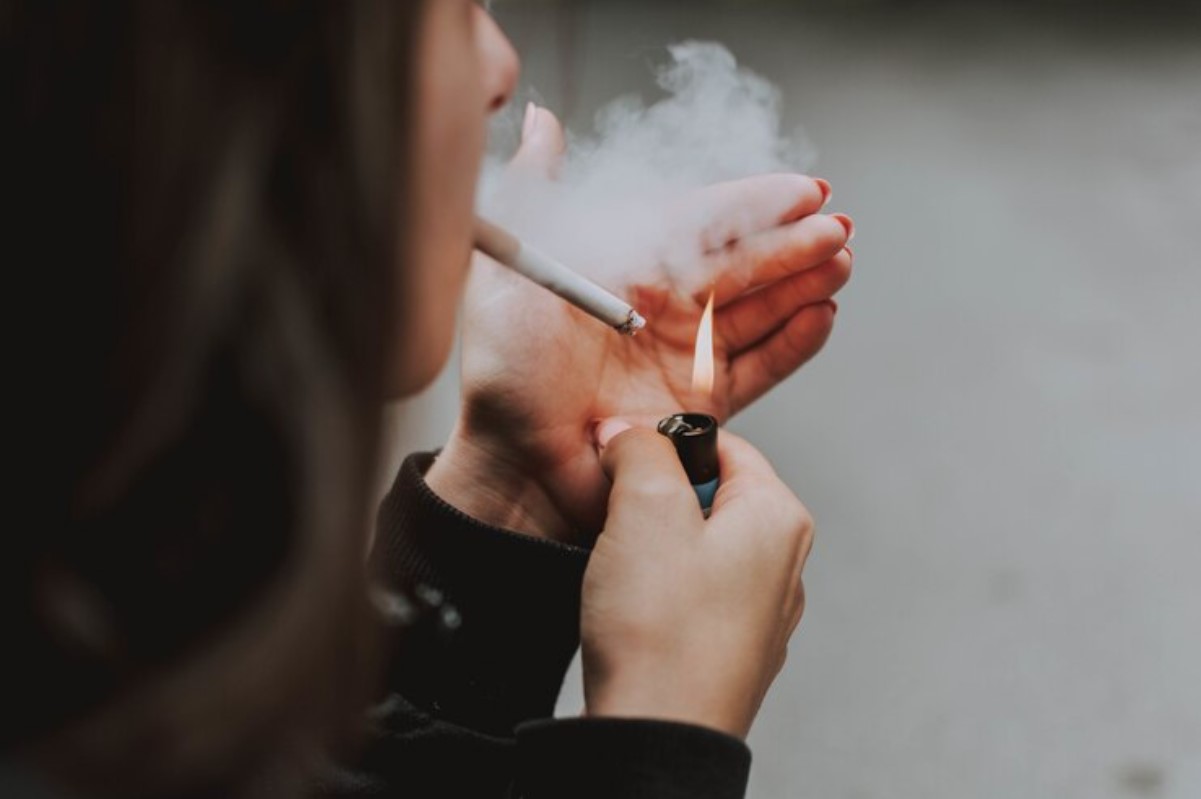 A person is pictured lighting a cigarette in public