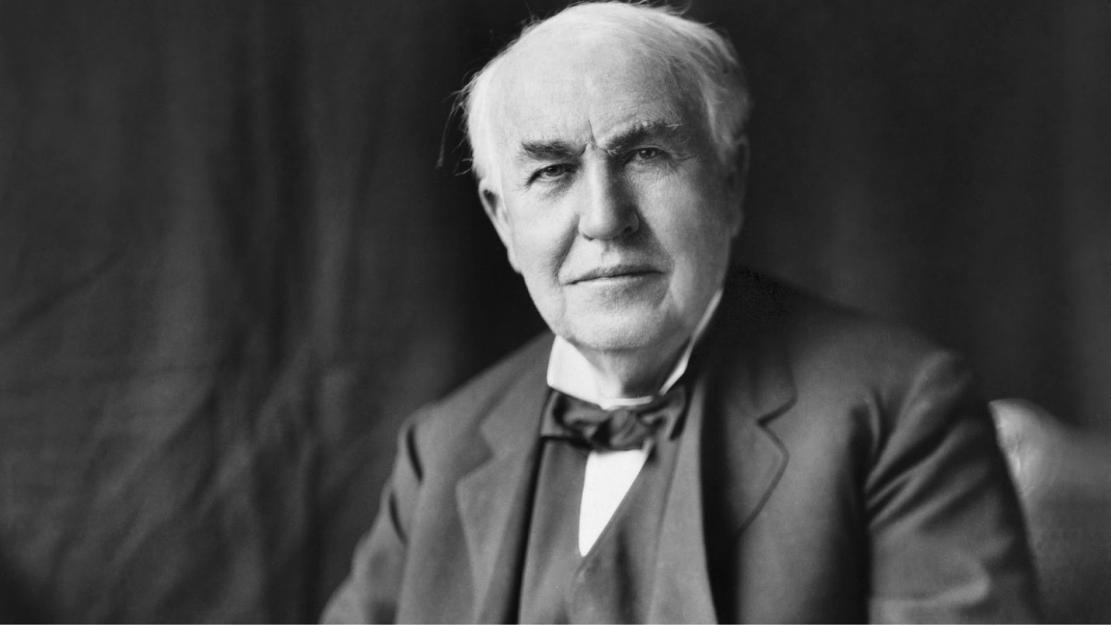 A black and white portrait of Thomas Edison in a suit.