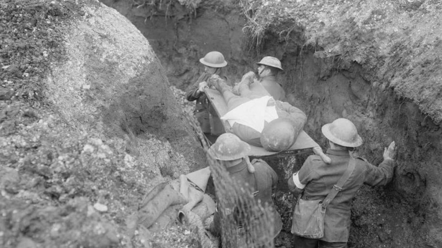Black and white photo showing World War I medics in a trench, transporting a wounded soldier on a stretcher