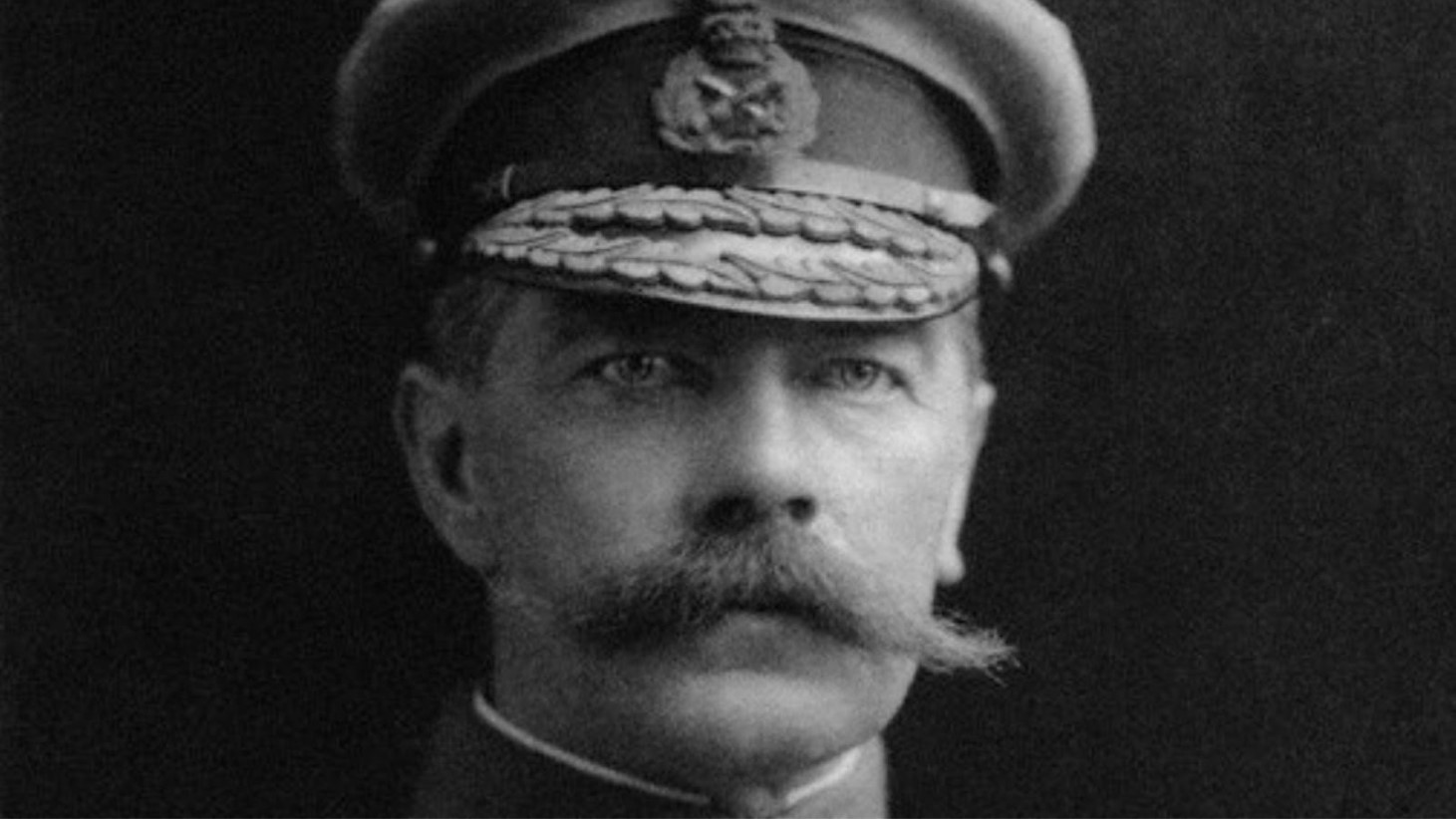 Black and white photograph of a stern-looking military officer in a dress uniform. He has a neatly trimmed mustache and is wearing a cap with a badge on the front