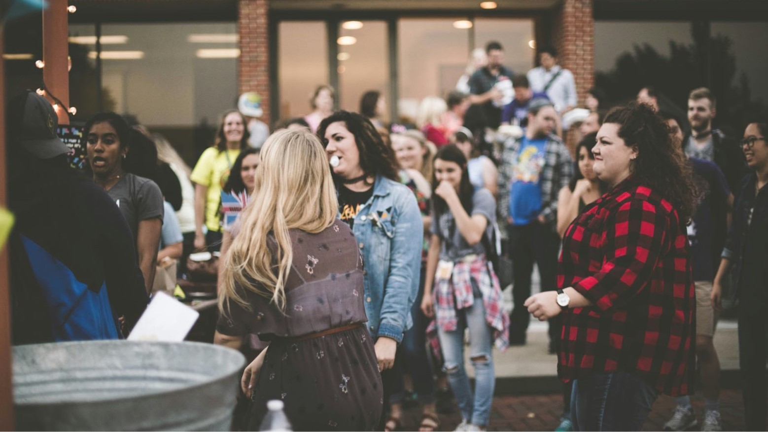 A group of young people gather in the outdoor area of a brick high school