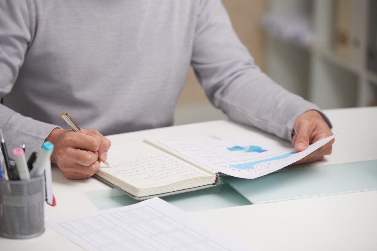 Man in white sweater works on research paper