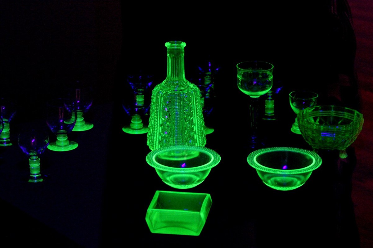 An image of several Vaseline glass items pictured in a dark room