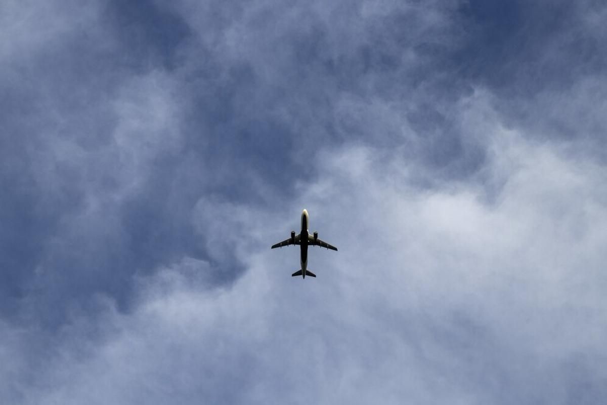 Plane flying through the sky with clouds in the background