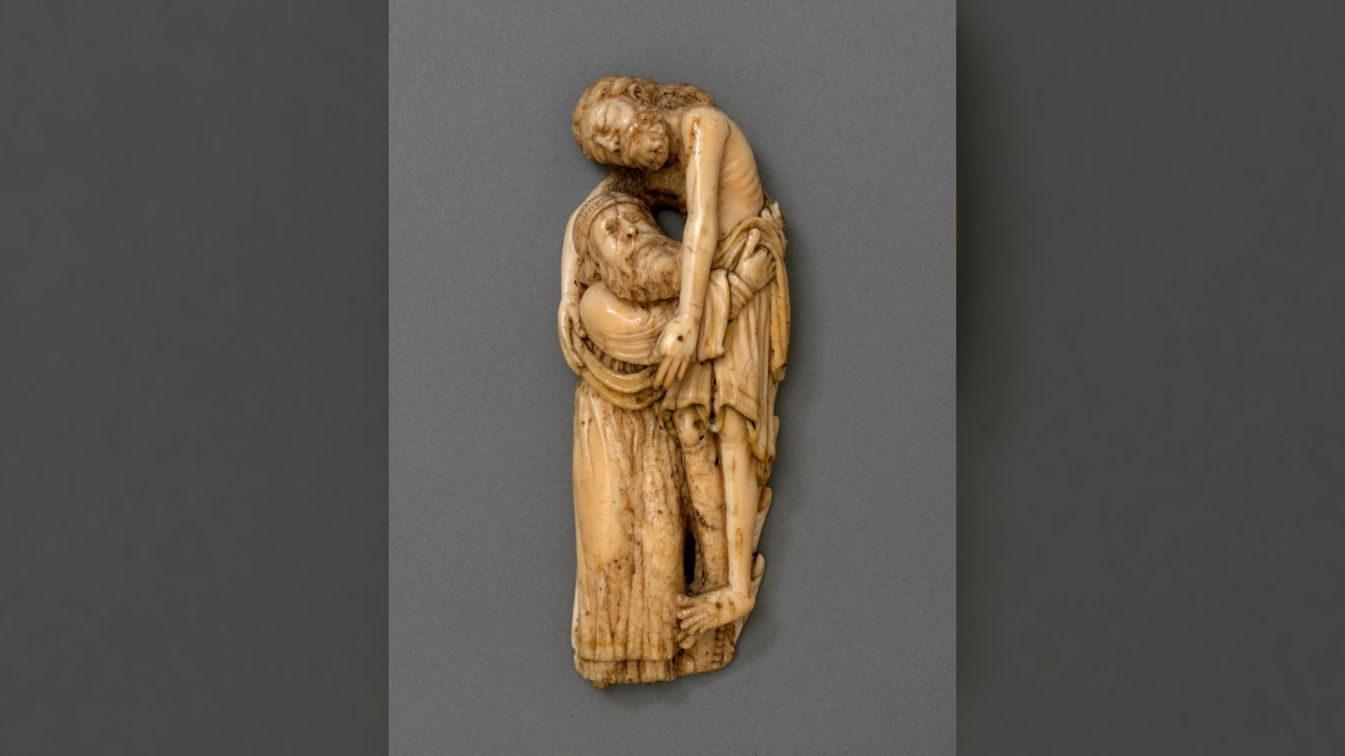 An aged ivory sculpture of a man lowering Jesus from the cross