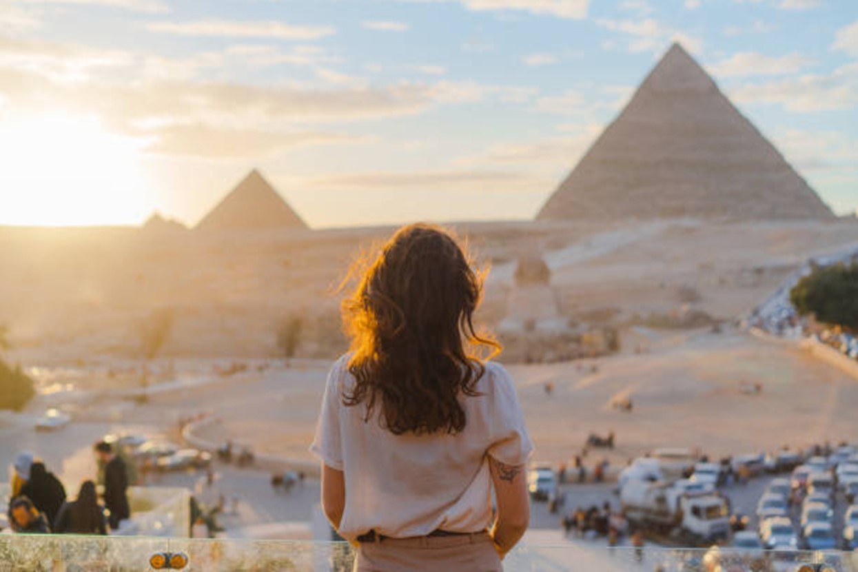 Modern-day woman looks over the Great Pyramids Giza of Ancient Egypt