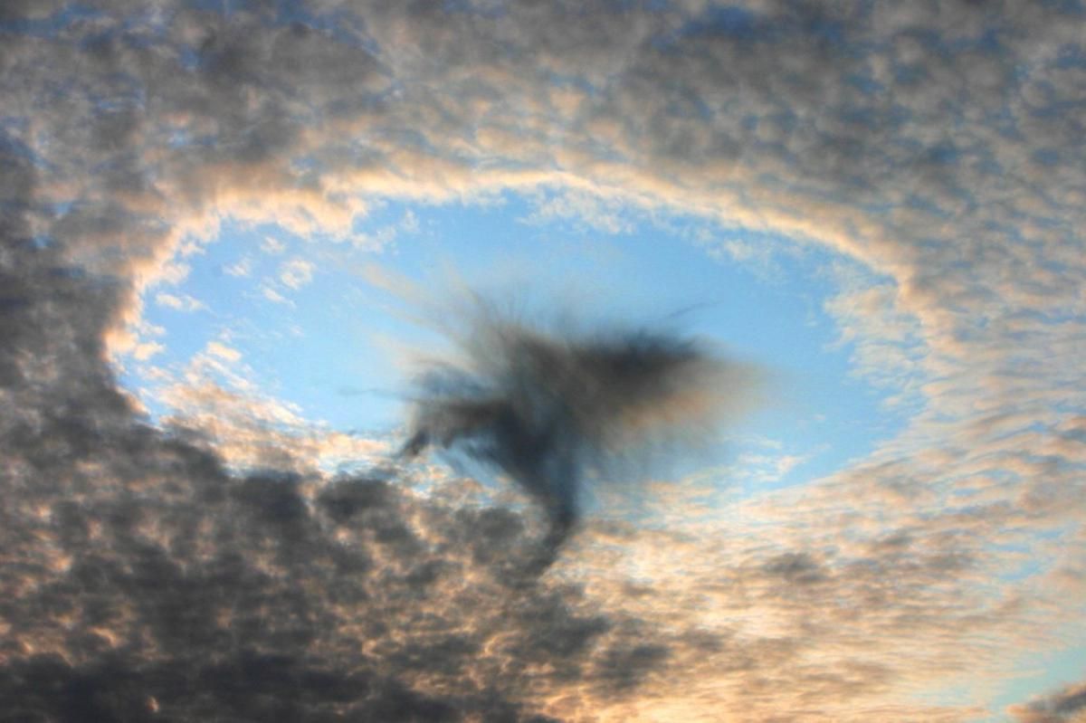 Photograph of a circular cavum cloud created by an airplane flying through a altocumulus cloud at a sharp angle
