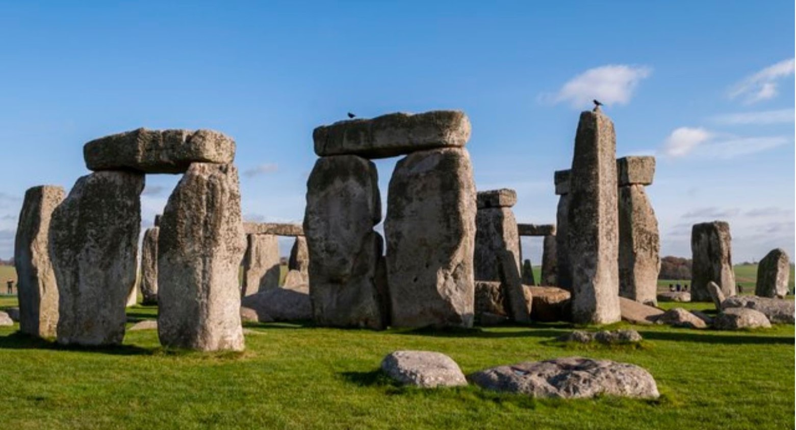 Stonehenge during daytime. Along with the Stonehenge stones, there are some smaller rocks surrounding them.