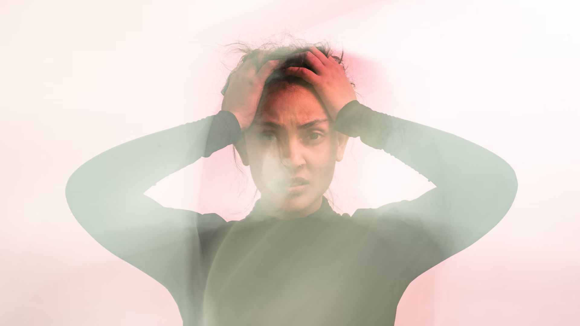 A slightly blurred photo of a woman holding her head with her hands.