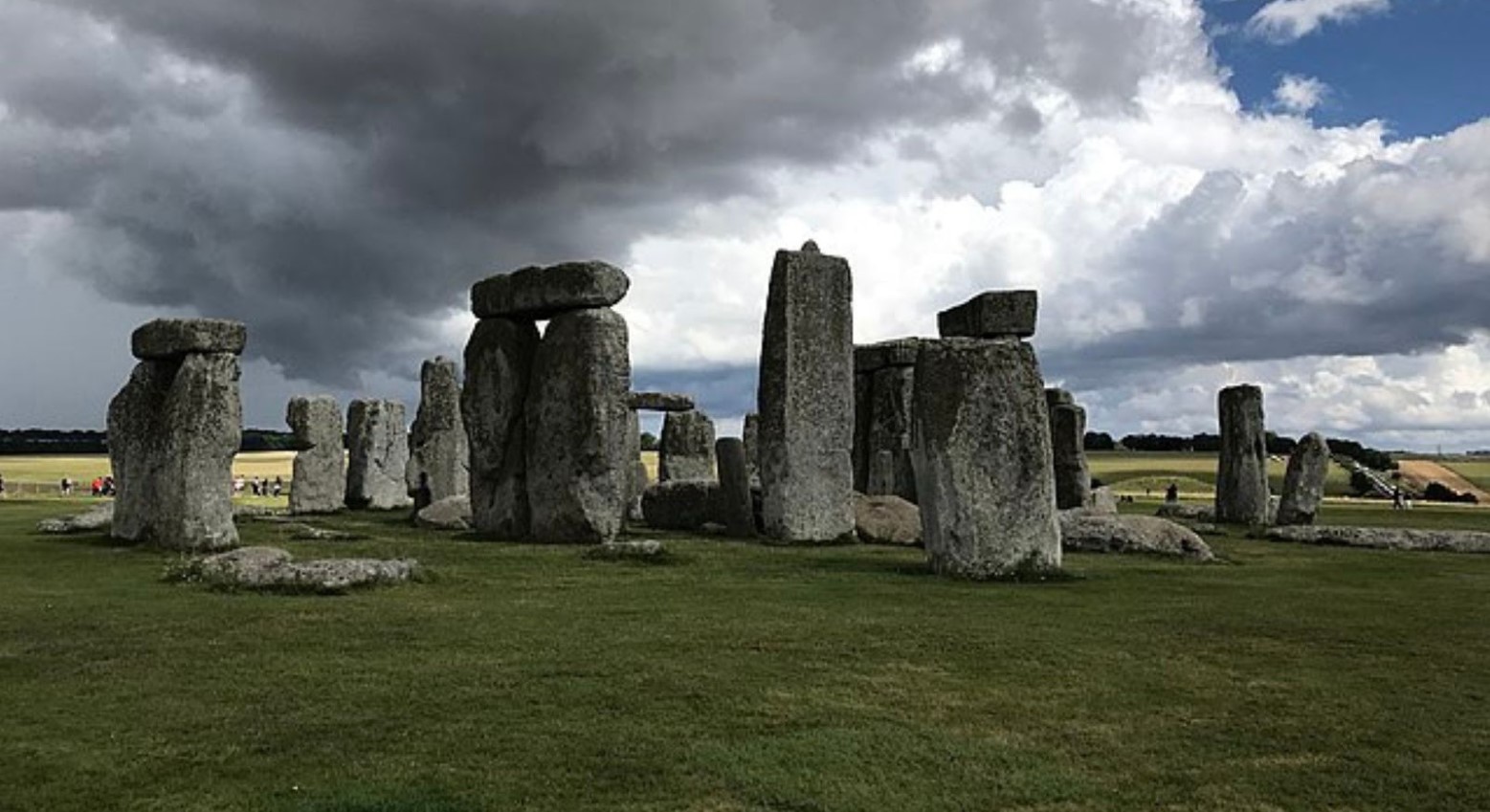 Stonehenge on a cloudy day. Some of the stones are in a circle, whereas others are off to the side.