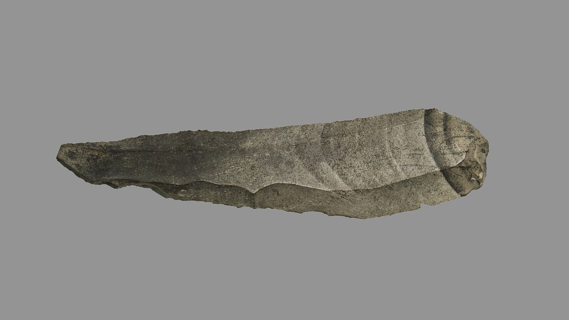 An isolated image of an ancient flint tool with a pointed end and sharp edges against a solid gray background