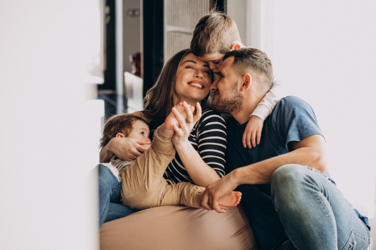 A young family pictured smiling together as they sit on the couch