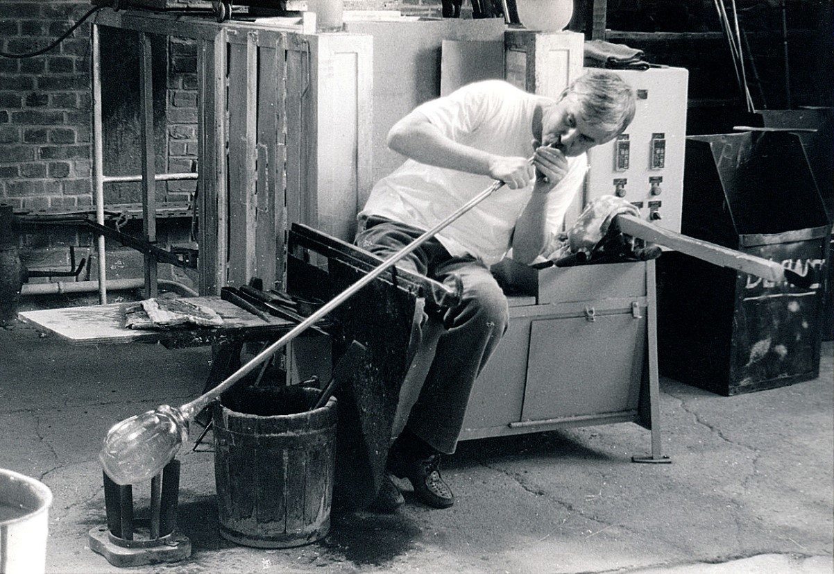 A image of a man blowing glass in his workshop