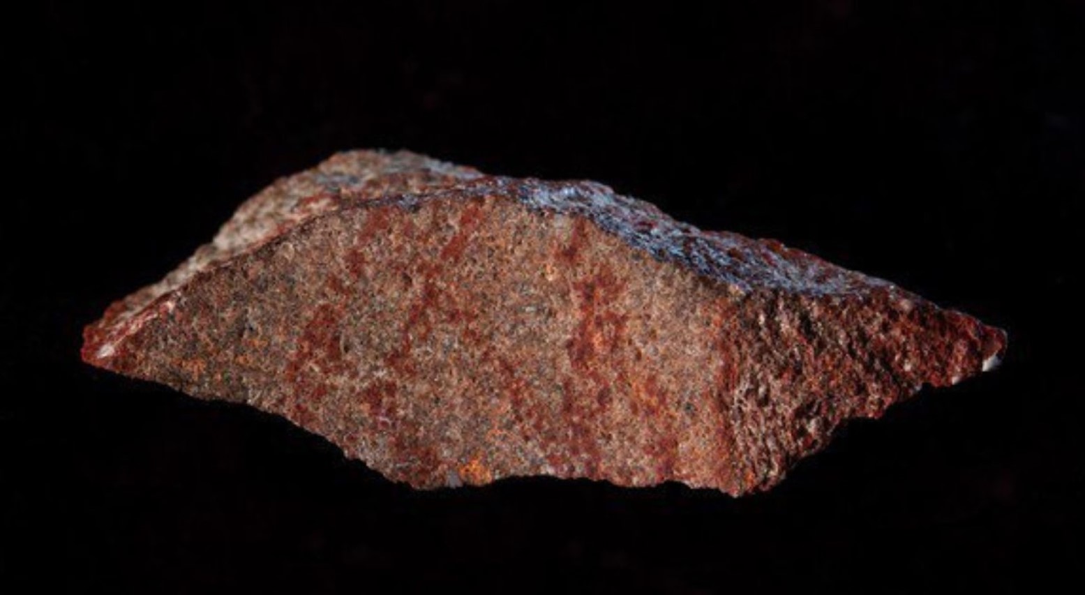 A close-up of some silcrete rock. The rock has bits of red in it but is mostly grey.