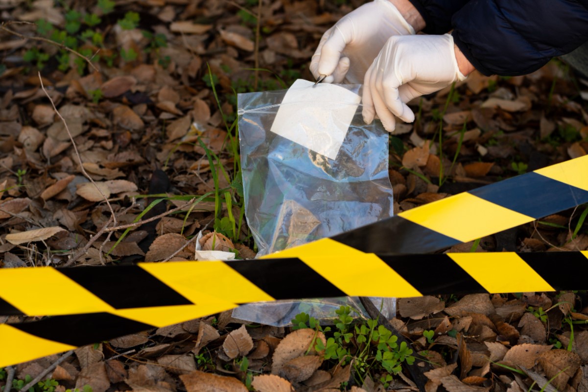 A crime scene investigator is pictured placing evidence into a plastic bag