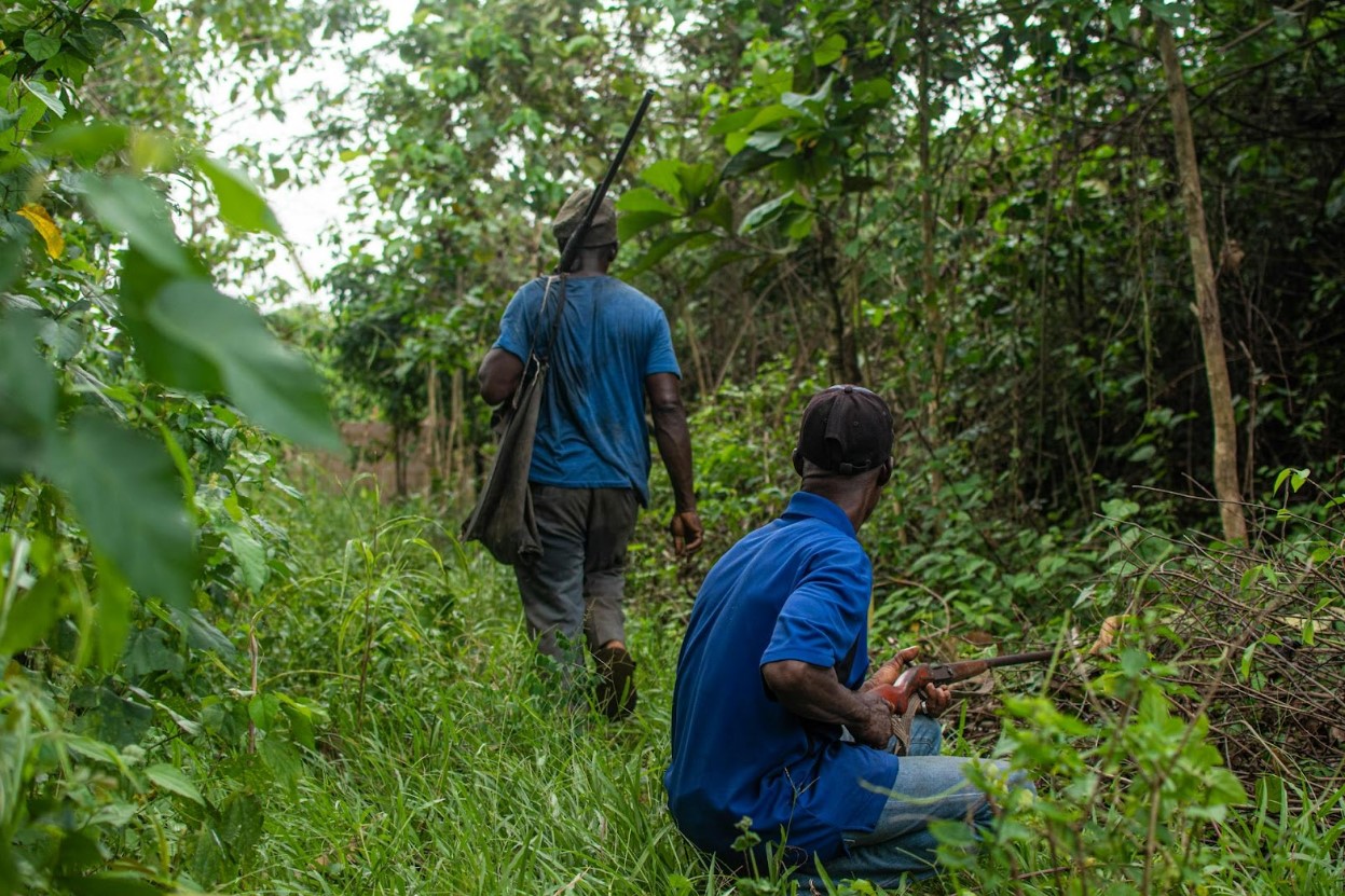 Two men holding rifles in the jungle