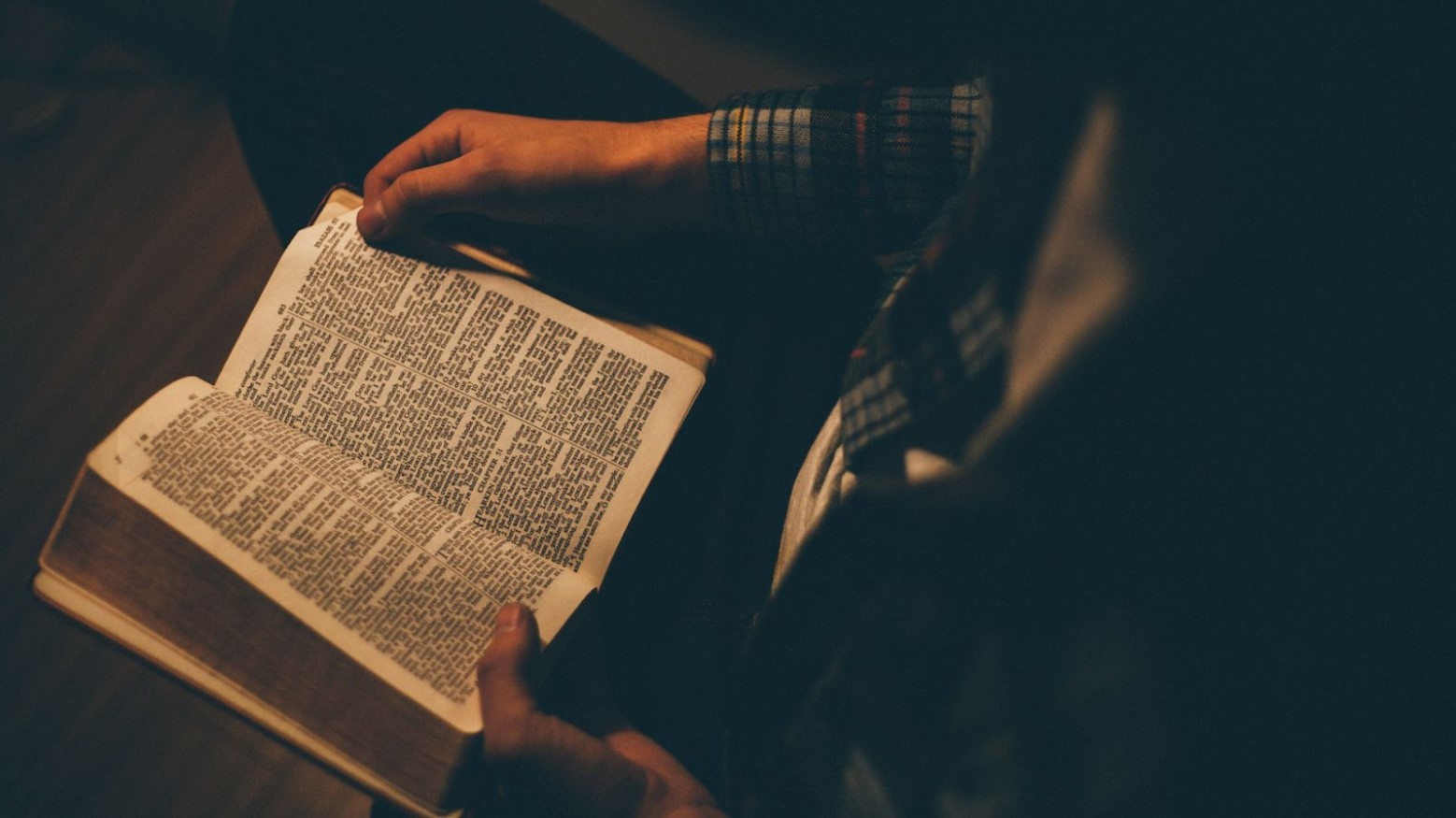 A young person stares down at the page of their Bible
