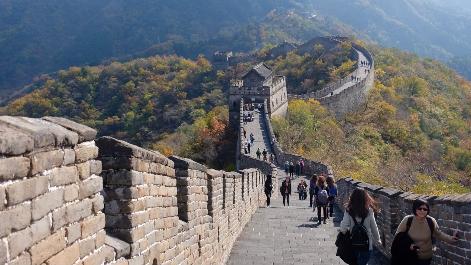 The Great Wall of China during summer. People are walking along the wall at various points.