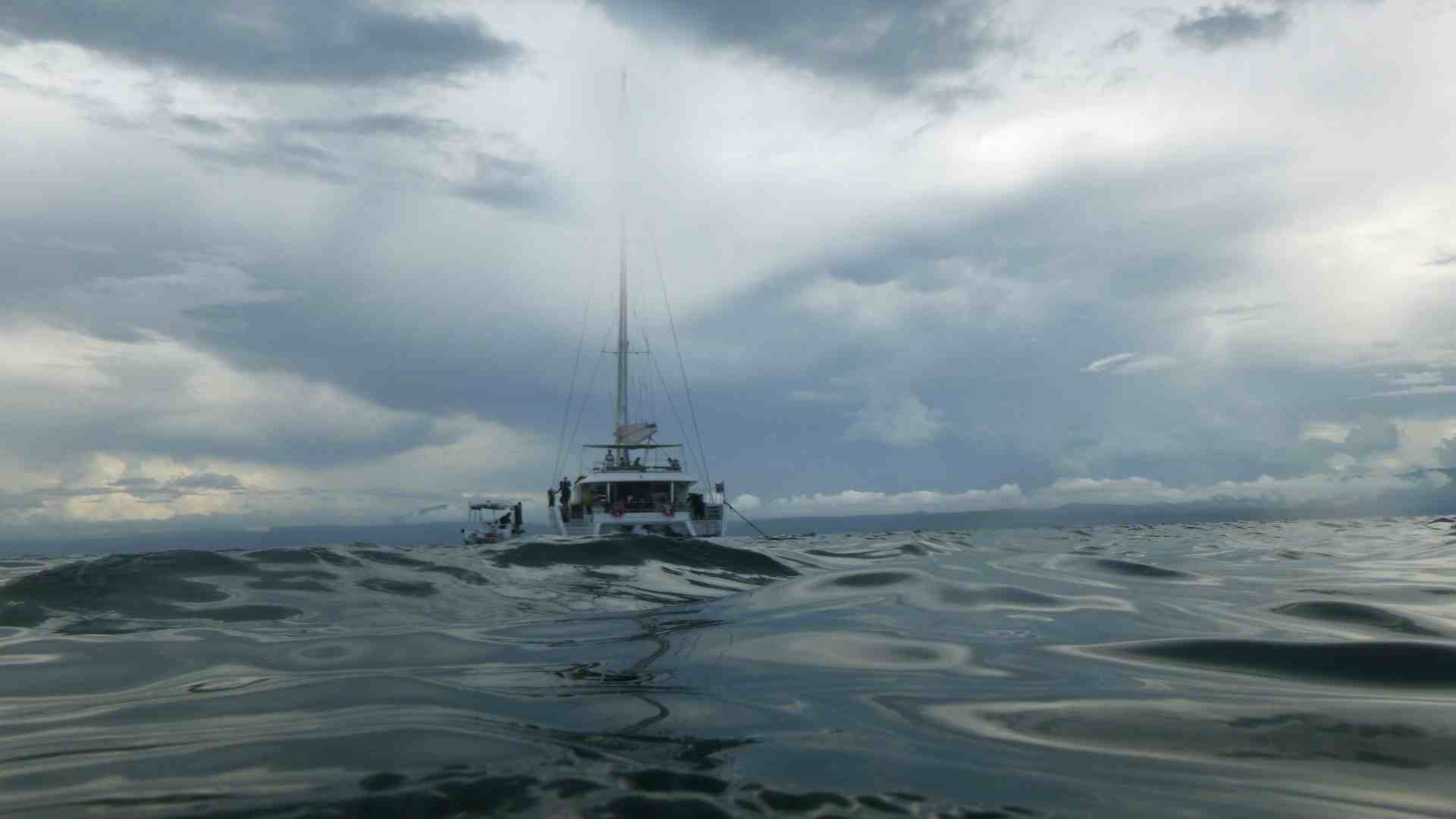 A boat floats away from the viewer as it goes on its way through the sea.