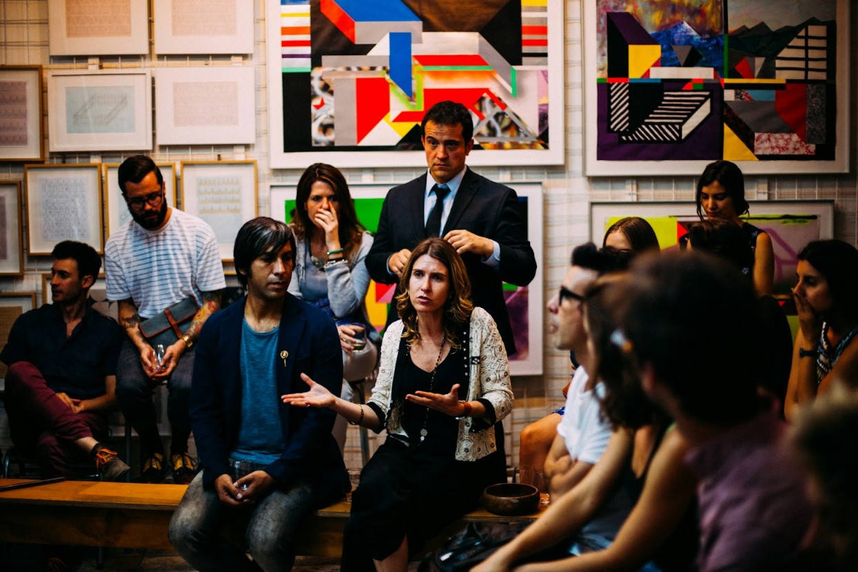 A woman speaking with hand gestures in a room full of people
