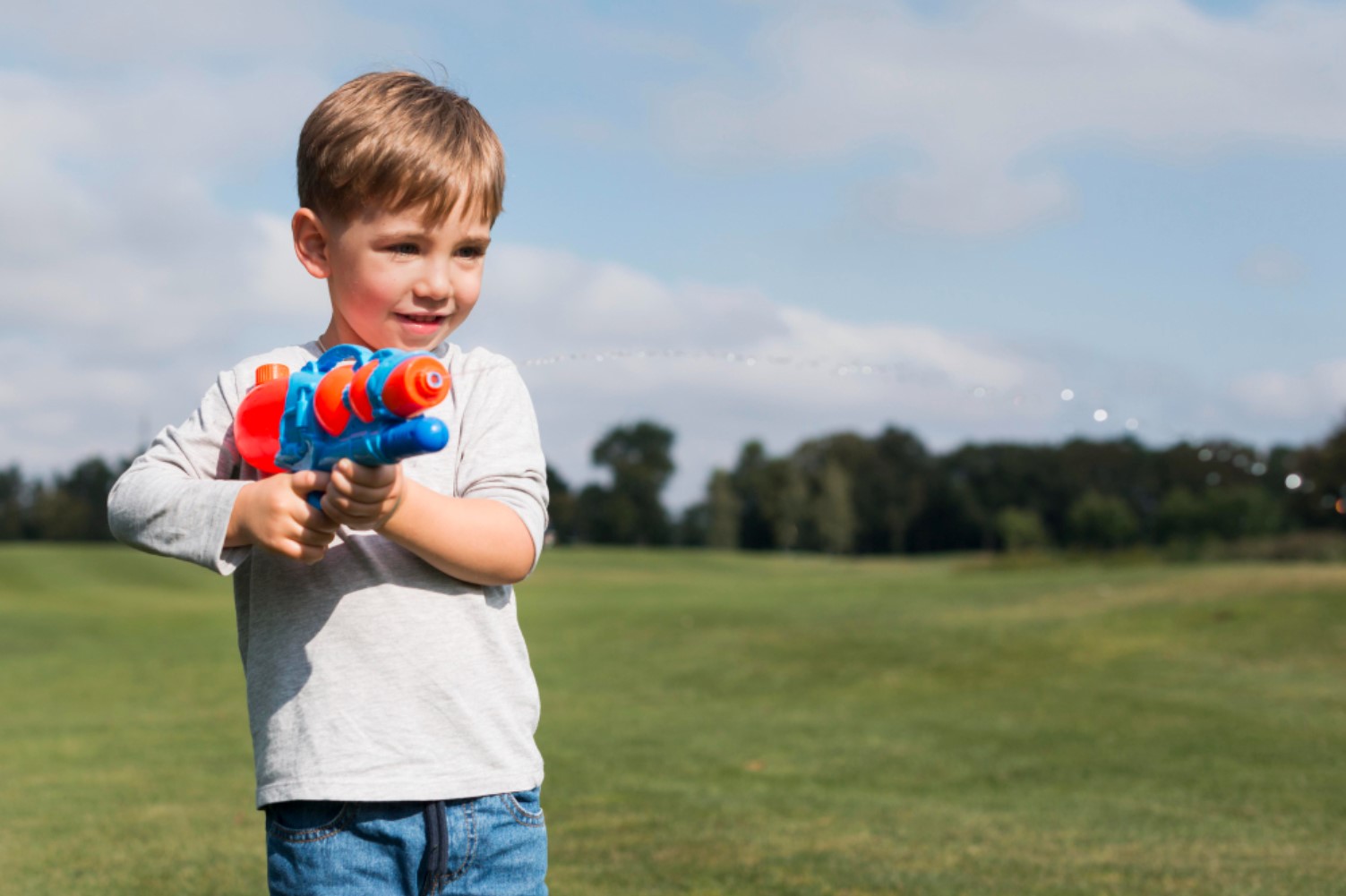 A young child pictured with an orange and blue water gun