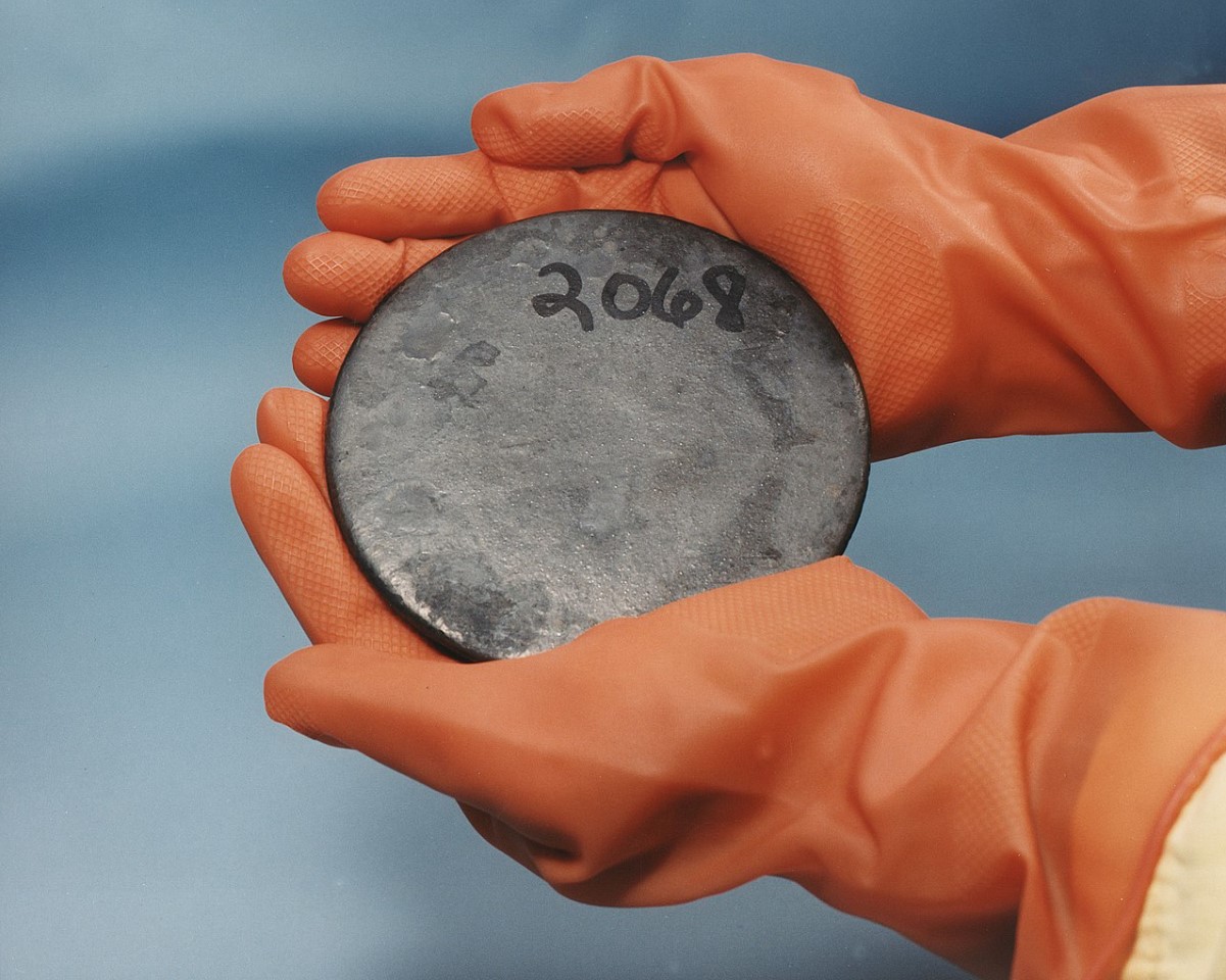 An image of a scientist holding a circular disk of uranium
