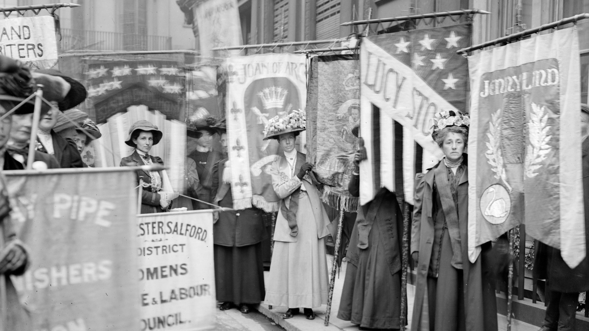 Suffragettes holding protest signs and marching in 1908.