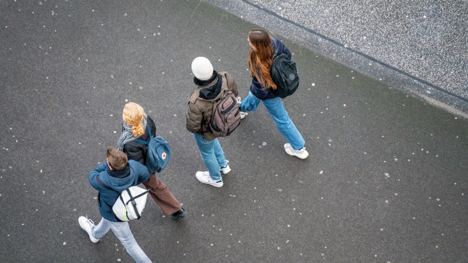 An aerial shot of kids walking to school with backpacks and winter coats