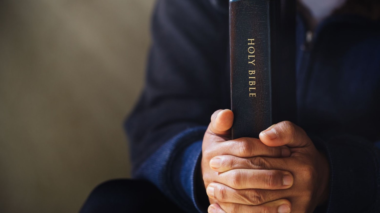 A man holds his hands around the Holy Bible