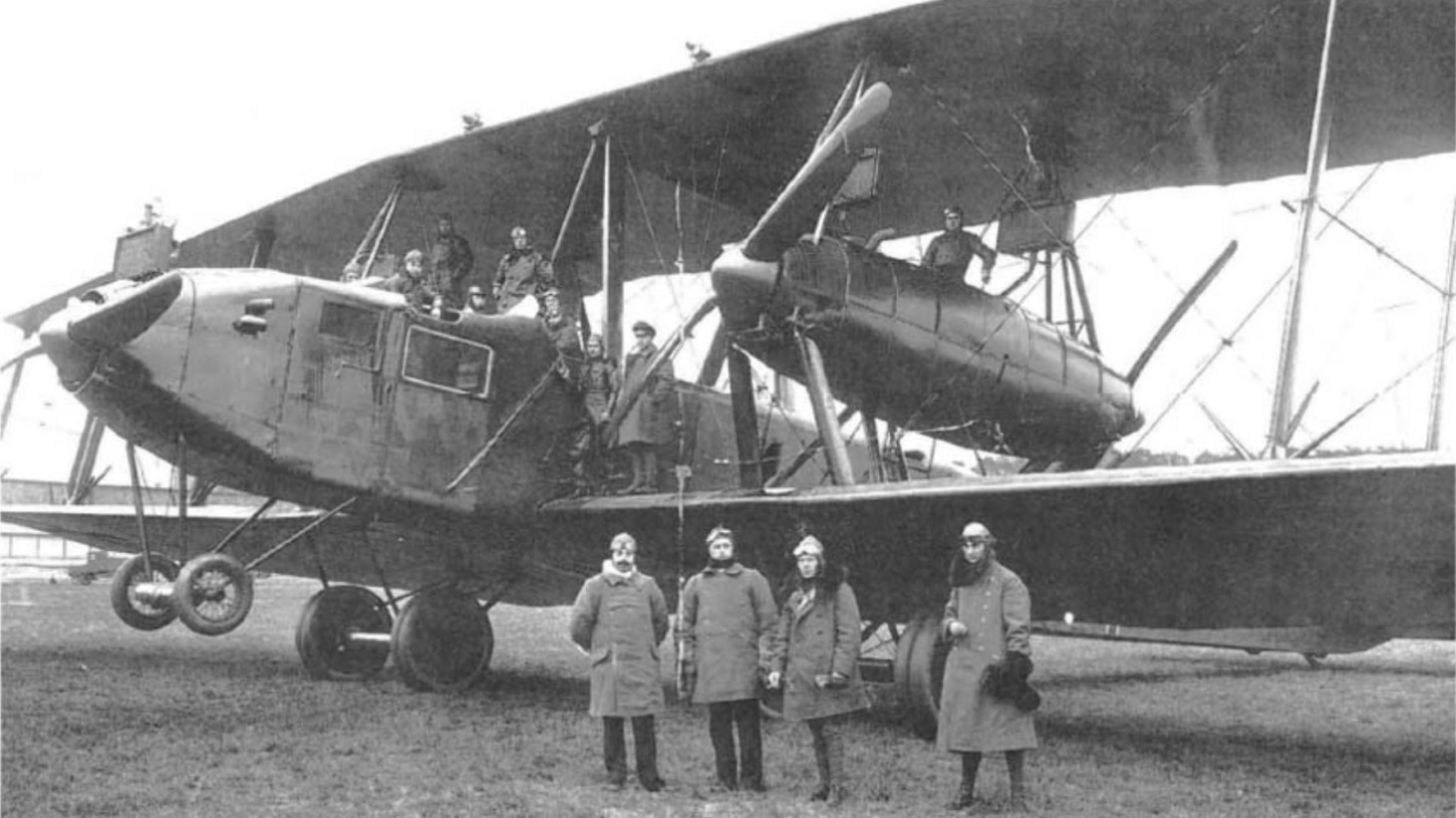 Black and white historical photo of a large early military seaplane with a crew on and around it