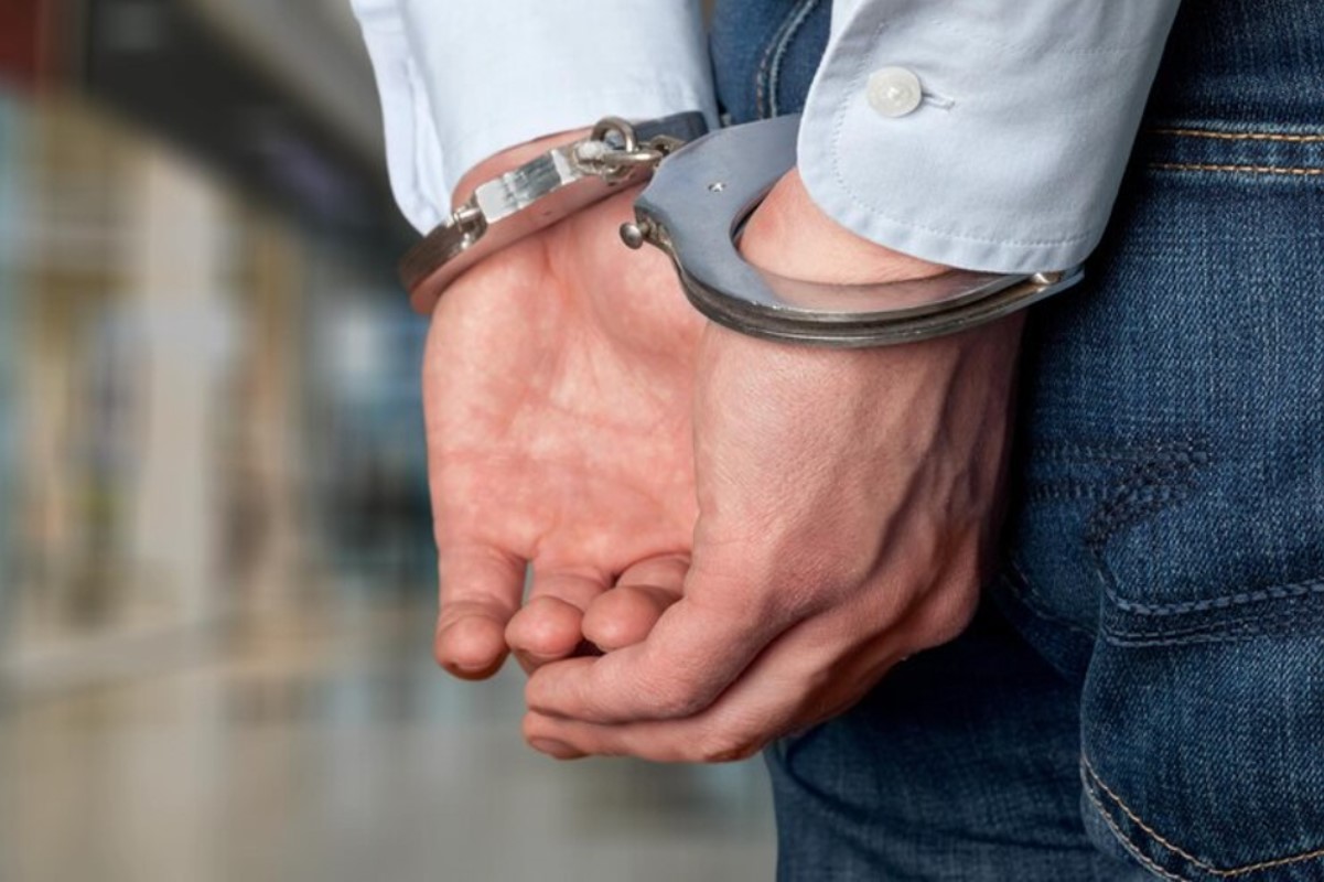 A man is pictured with his hands behind in back in cuffs
