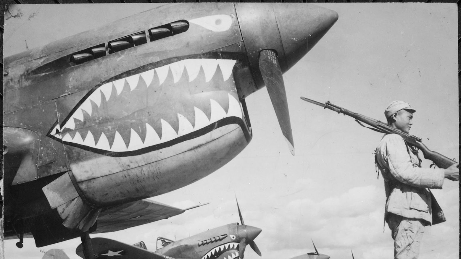 A WWII-era photograph showing a Chinese soldier standing guard in front of Flying Tigers planes.
