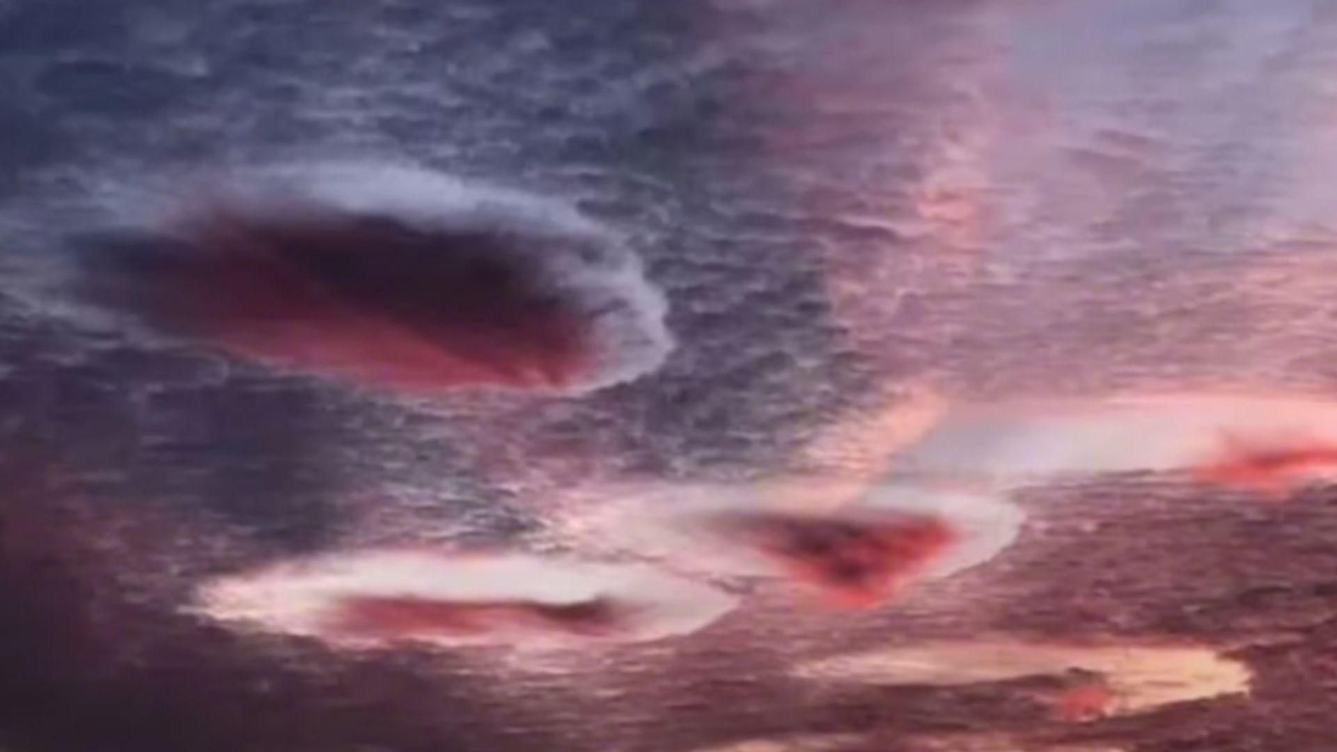 Several cavum clouds in a dark pink sky