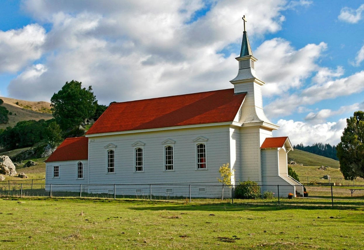 Red and white concrete church on green grass field