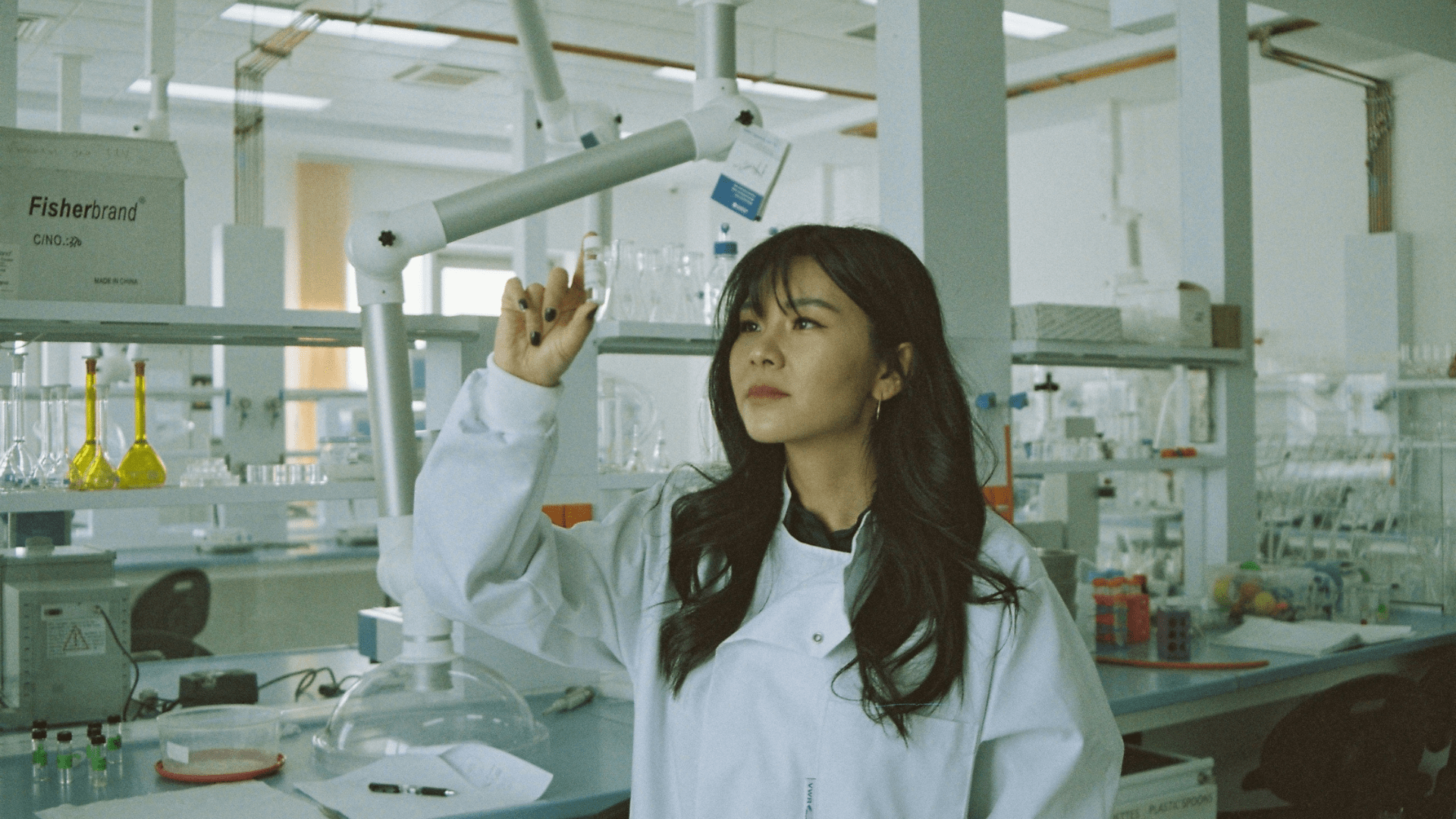 A young female scientist looks at a vial in the laboratory.