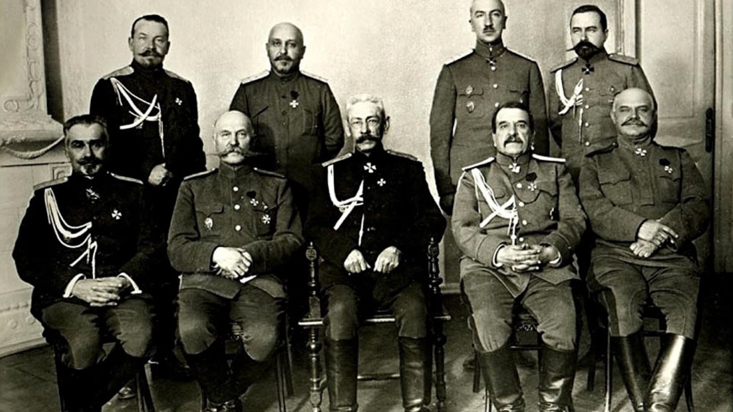 Black and white photograph of seven military officers posed for a formal picture. They are dressed in ornate uniforms with medals and decorations. The officers are arranged in two rows