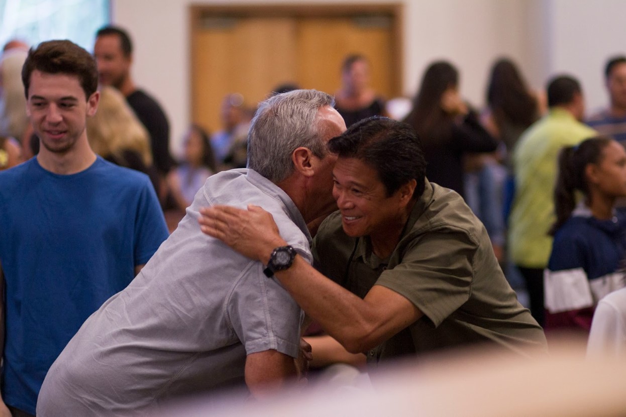 Two men embracing each other in a community setting