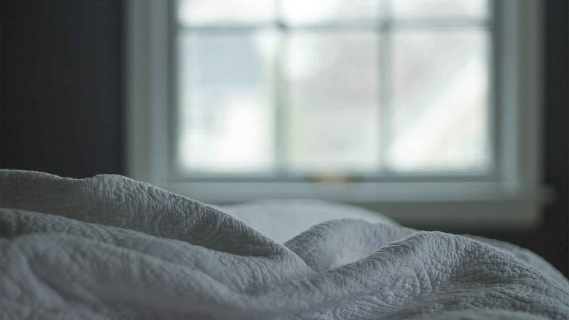 A bed with white linens and a window in the background