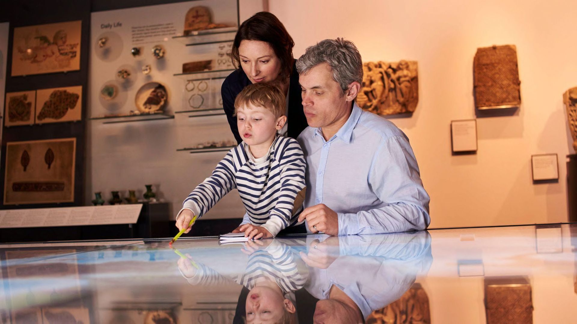 A shot of two adults and a child at an exhibit at a historical museum