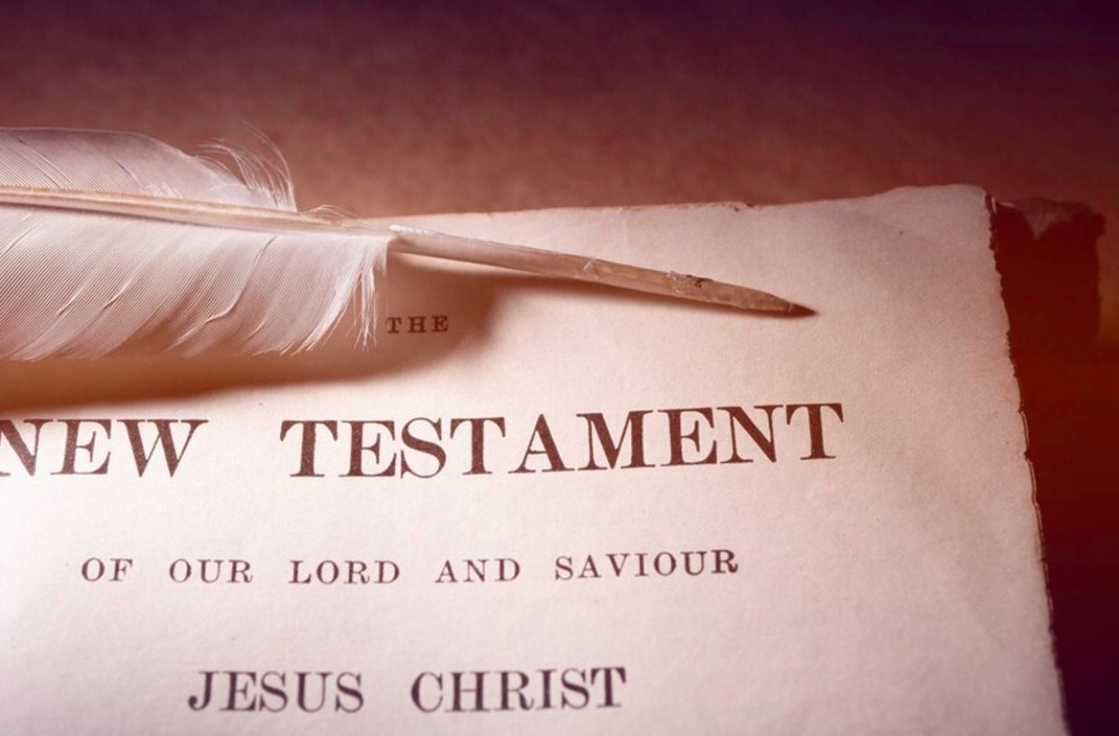 Close-up photo of the New Testament with a feather quill