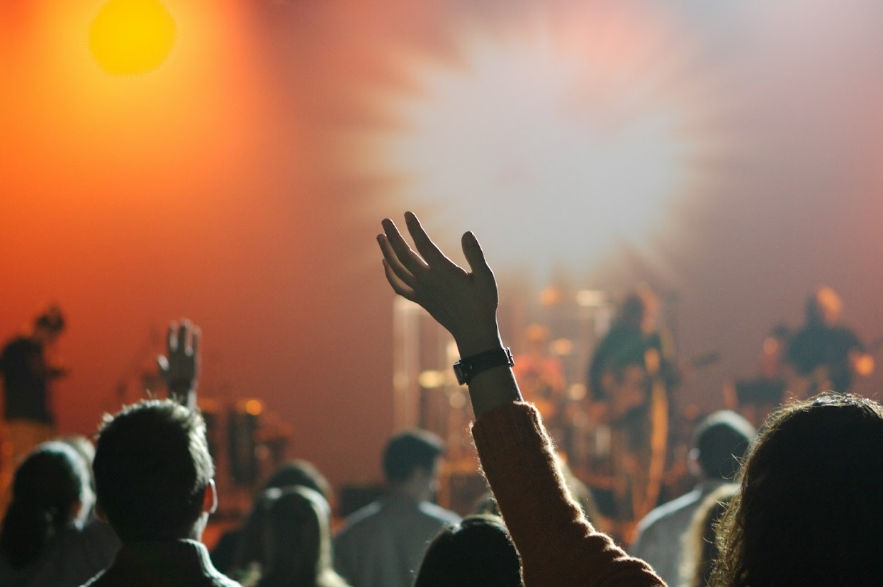 People raising their hands watching a show on stage