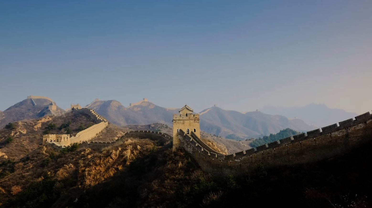 The Great Wall of China in daylight. The wall follows the hills around.