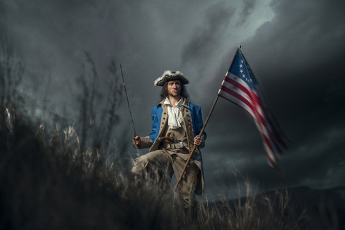 Illustration of a soldier in the Revolutionary War holding an American flag on the battlefield