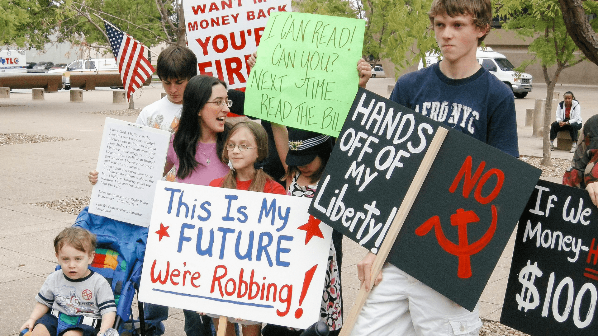 A group of children and teenagers stands holding protest signs.