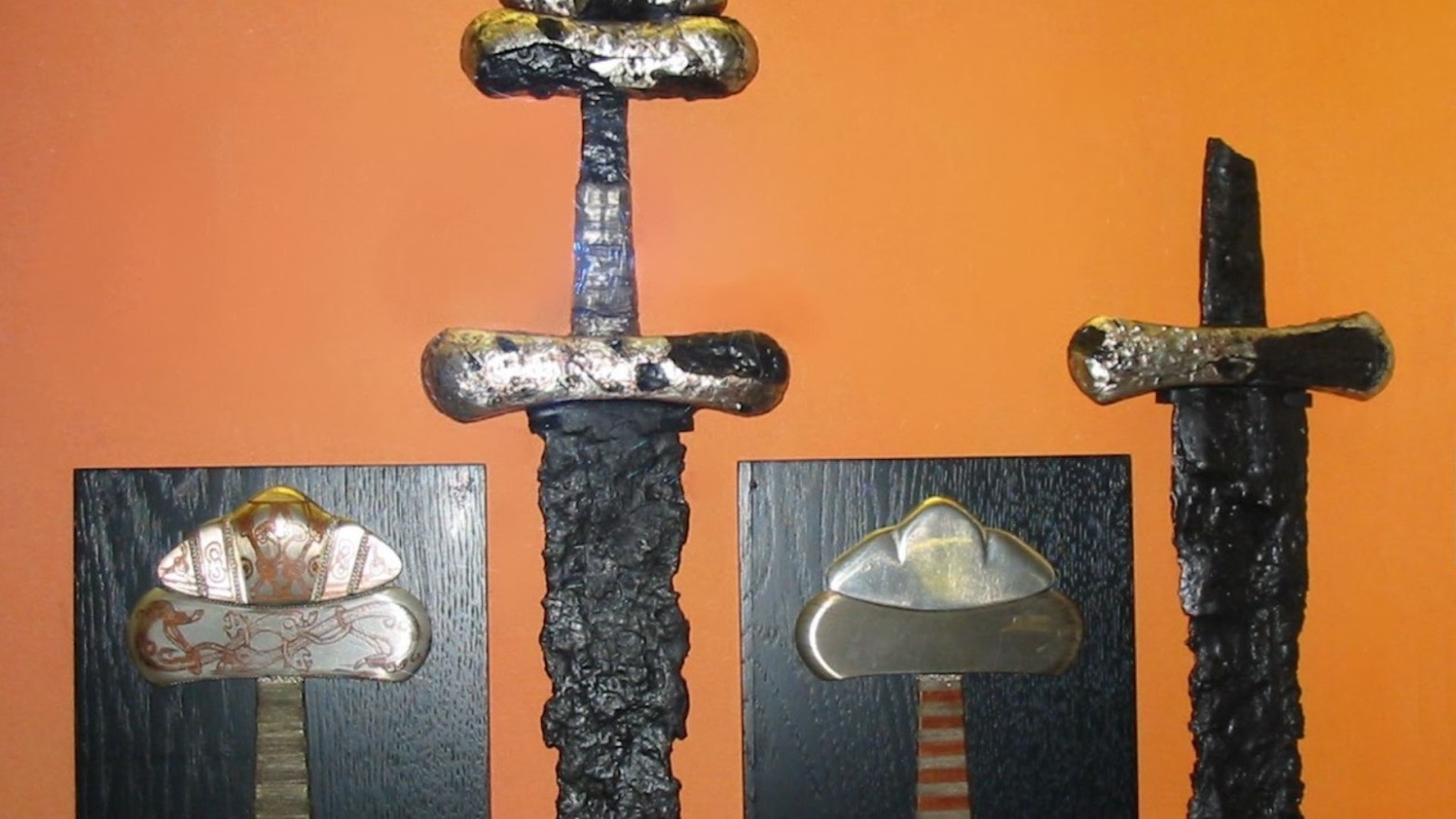 Examples of different types of ancient Viking swords’ pommels that have been found, against an orange background.