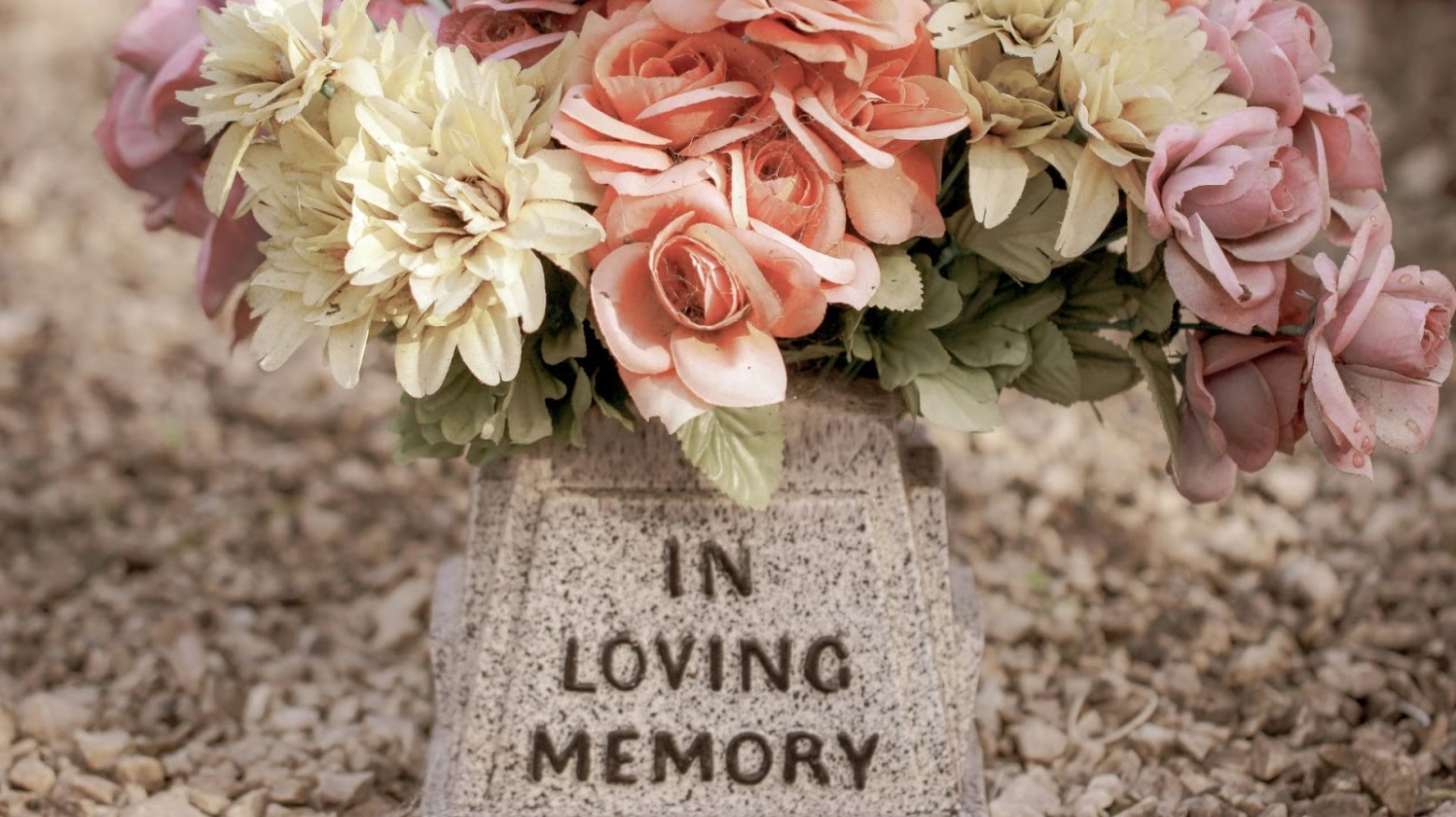A vase that says “In Loving Memory” with colorful flowers in it.