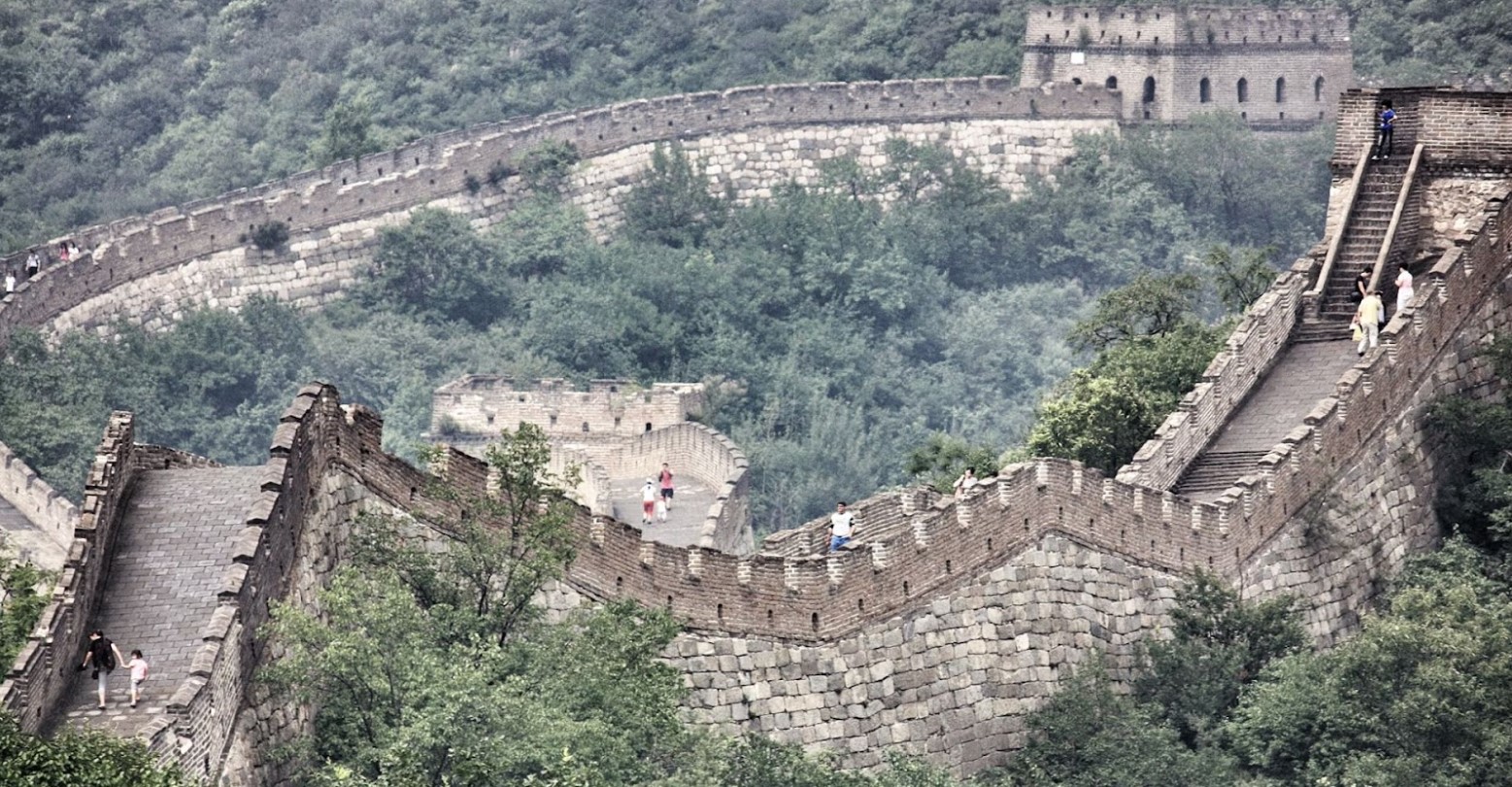 An aerial view of the Great Wall of China. People are walking along the wall at different points.