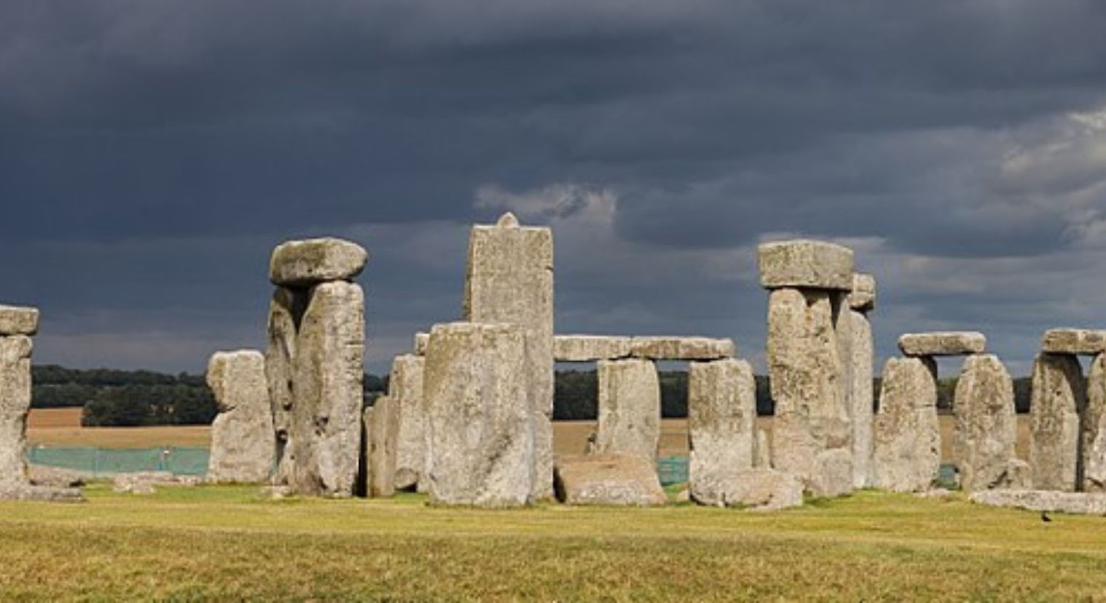 Stonehenge on a grey day. The stone are all mostly ground together, but there are one or two that are slightly off to the side.