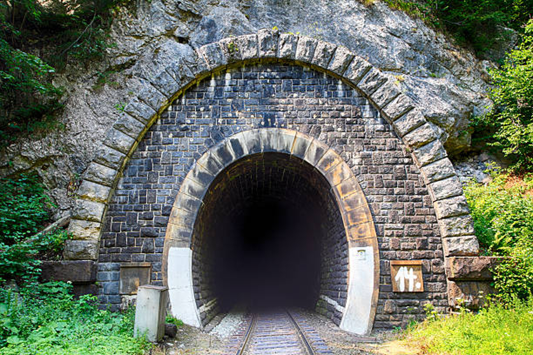 Photograph of railroad tracks leading into an underground tunnel